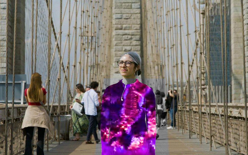 A woman in colourful light on a bridge among pedestrians