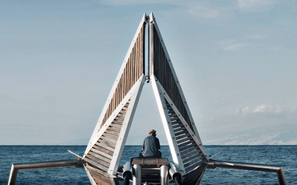 A triangular wooden structure on a boat looks out to the open sea