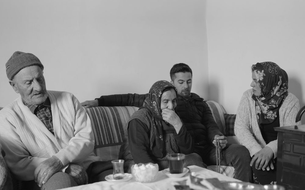 Black and white photo of a family sitting together on a sofa with tea